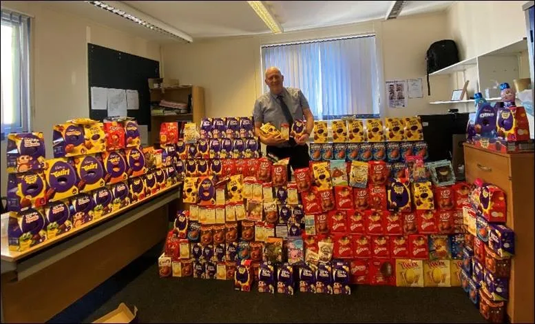 A hall filled with hundreds of donated Easter eggs stacked across tables, with a volunteer standing behind them