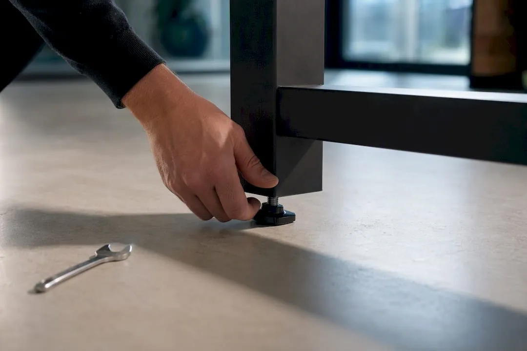 Hand adjusting standing desk foot