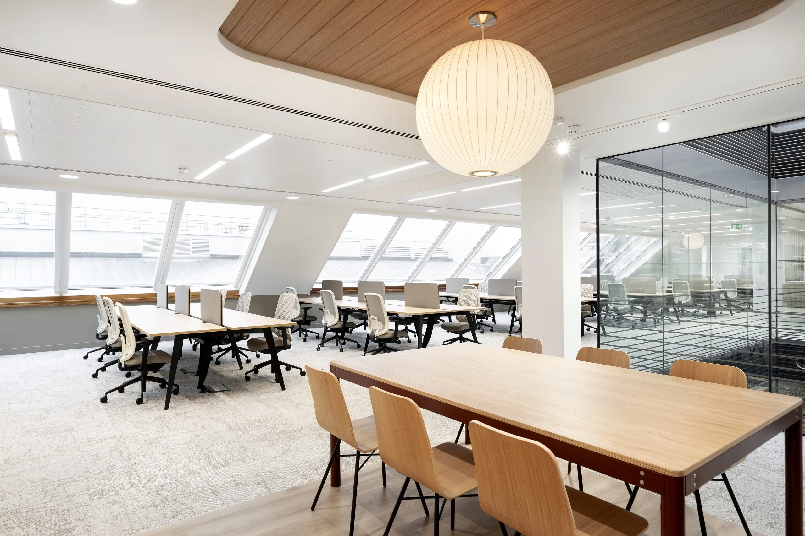 Open-plan office with timber tables beneath large paper pendant lights