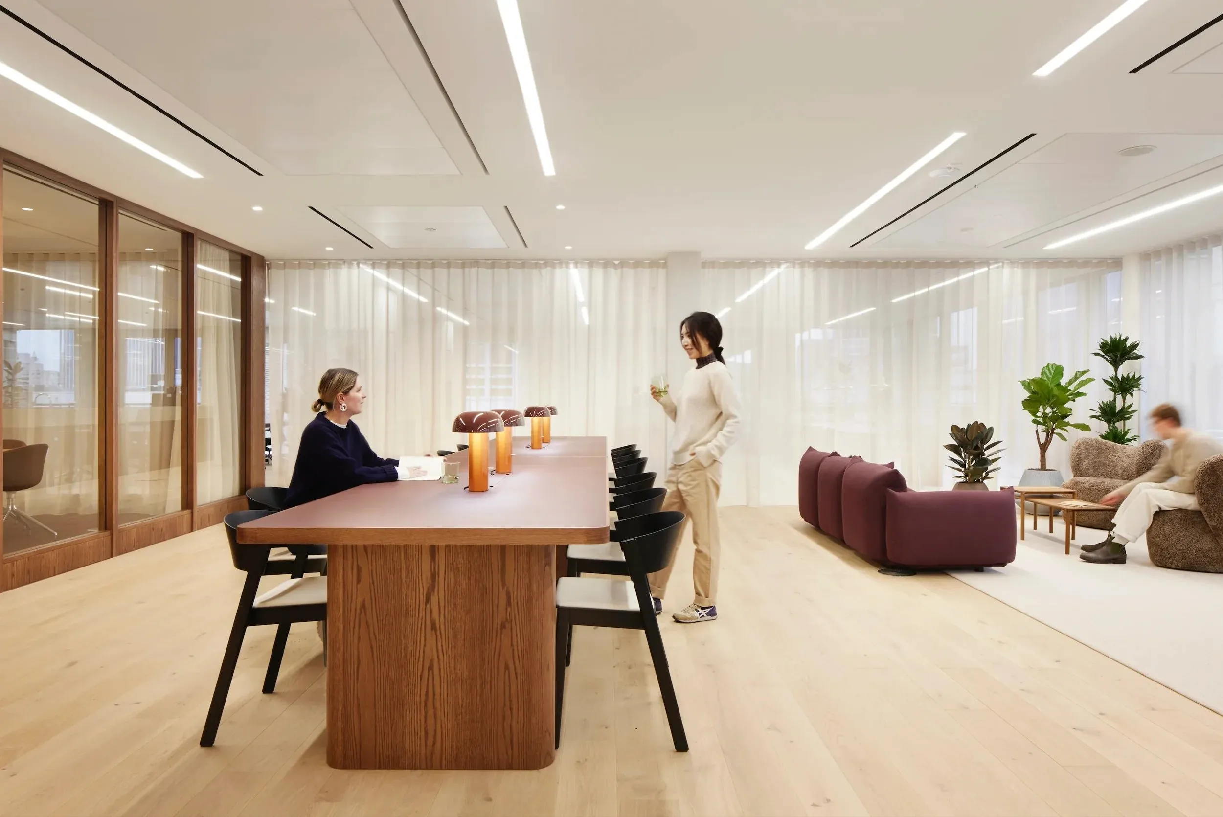 Meeting area with a timber table, pendant lights and soft seating
