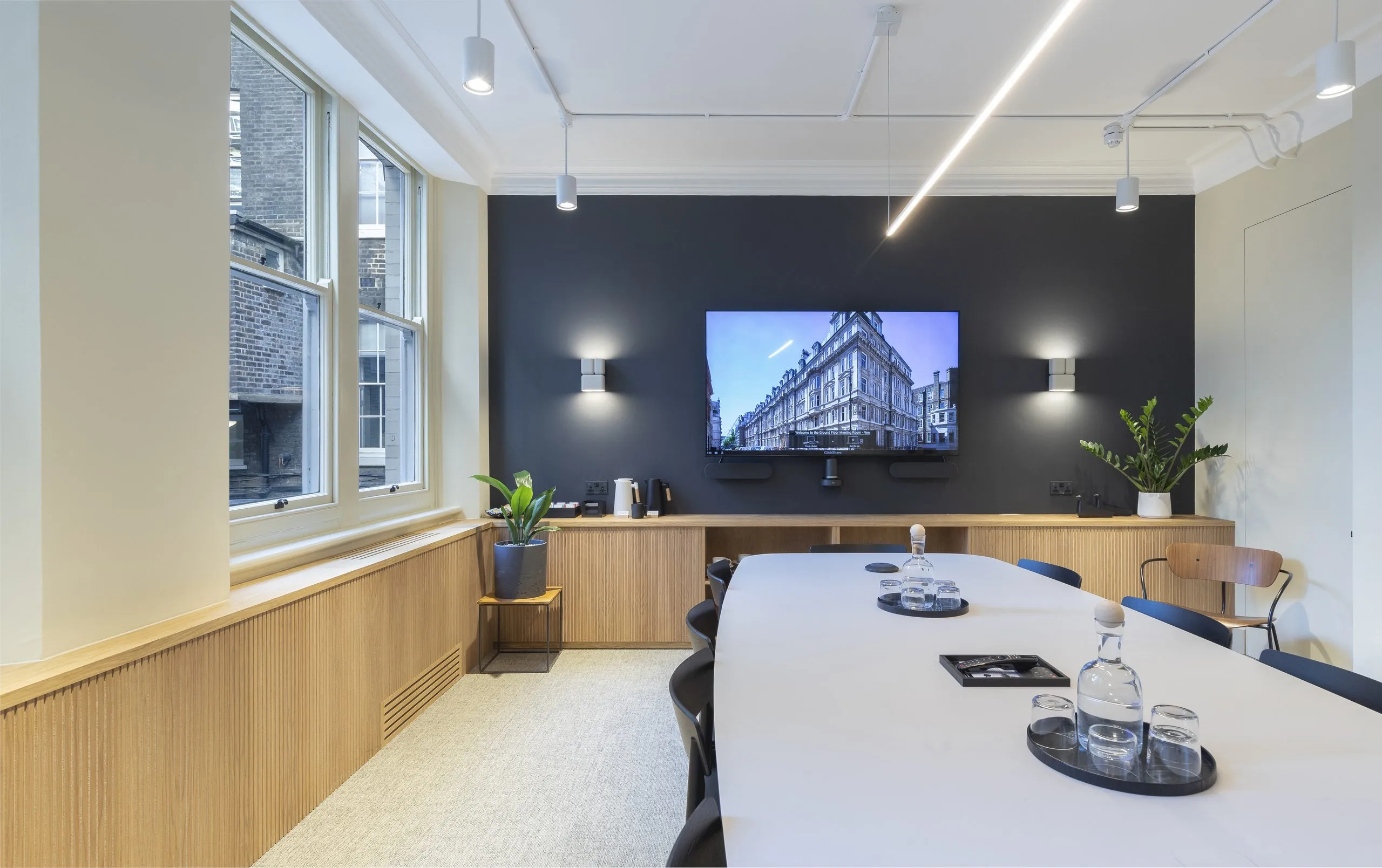 Boardroom with a long white table and a wall-mounted screen