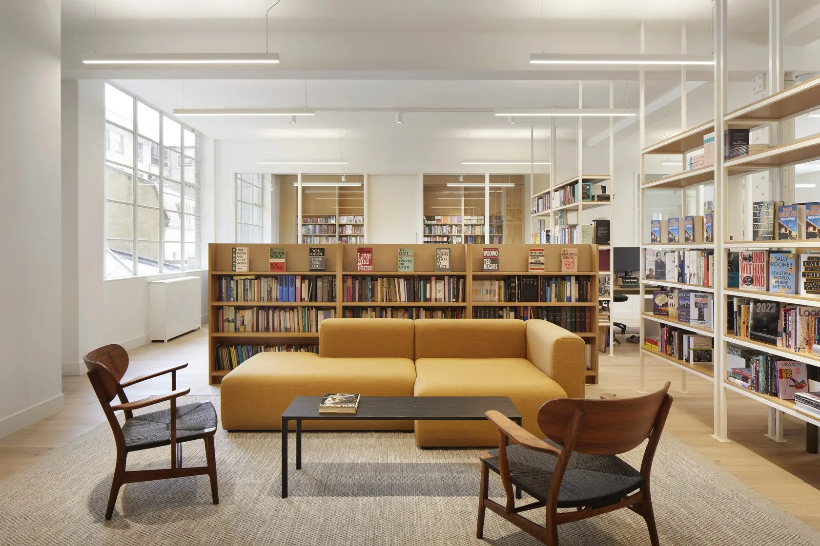 Library lounge with a mustard sofa, armchairs and tall bookshelves