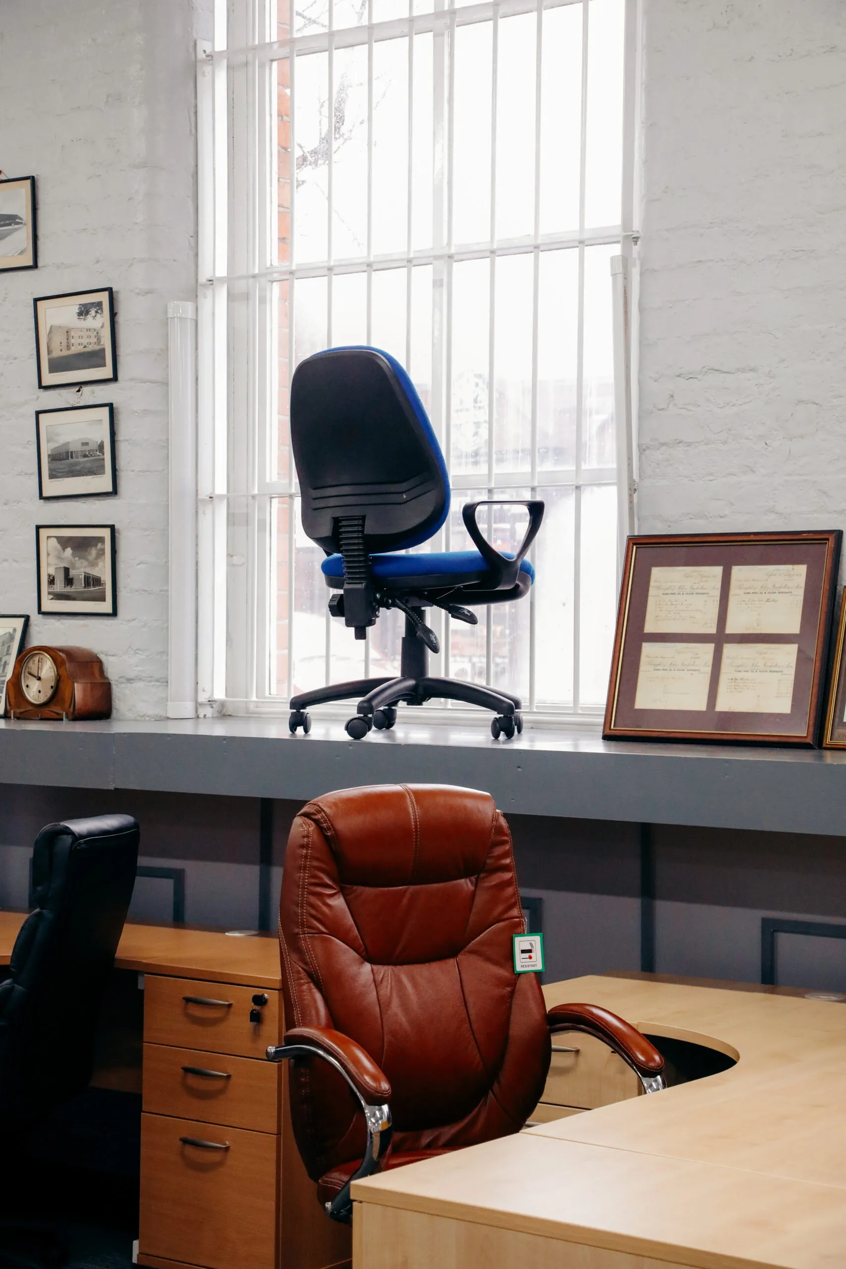 Brown leather executive chair and blue operator chair at a corner desk