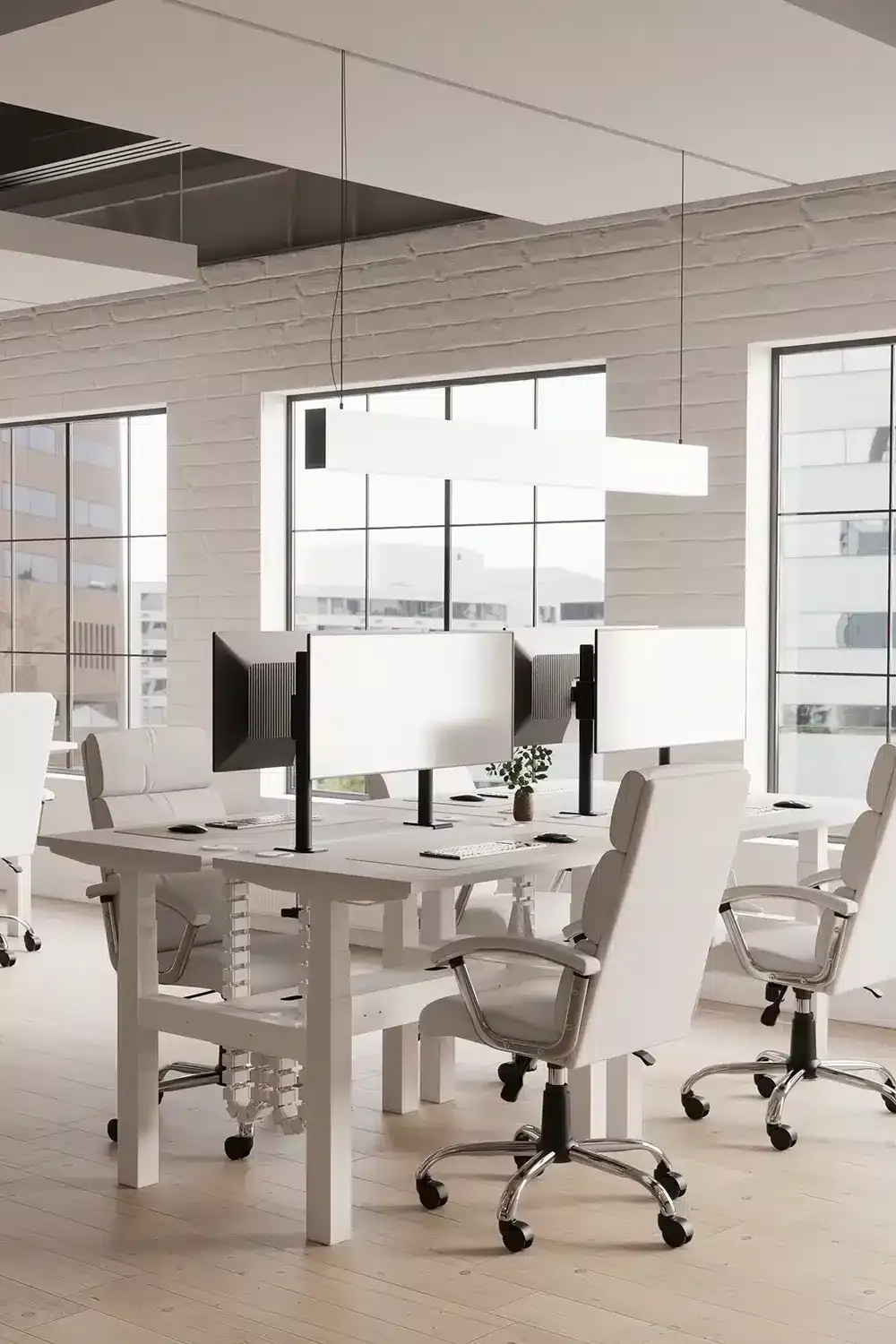 White height adjustable bench desks with grey office chairs in a bright office