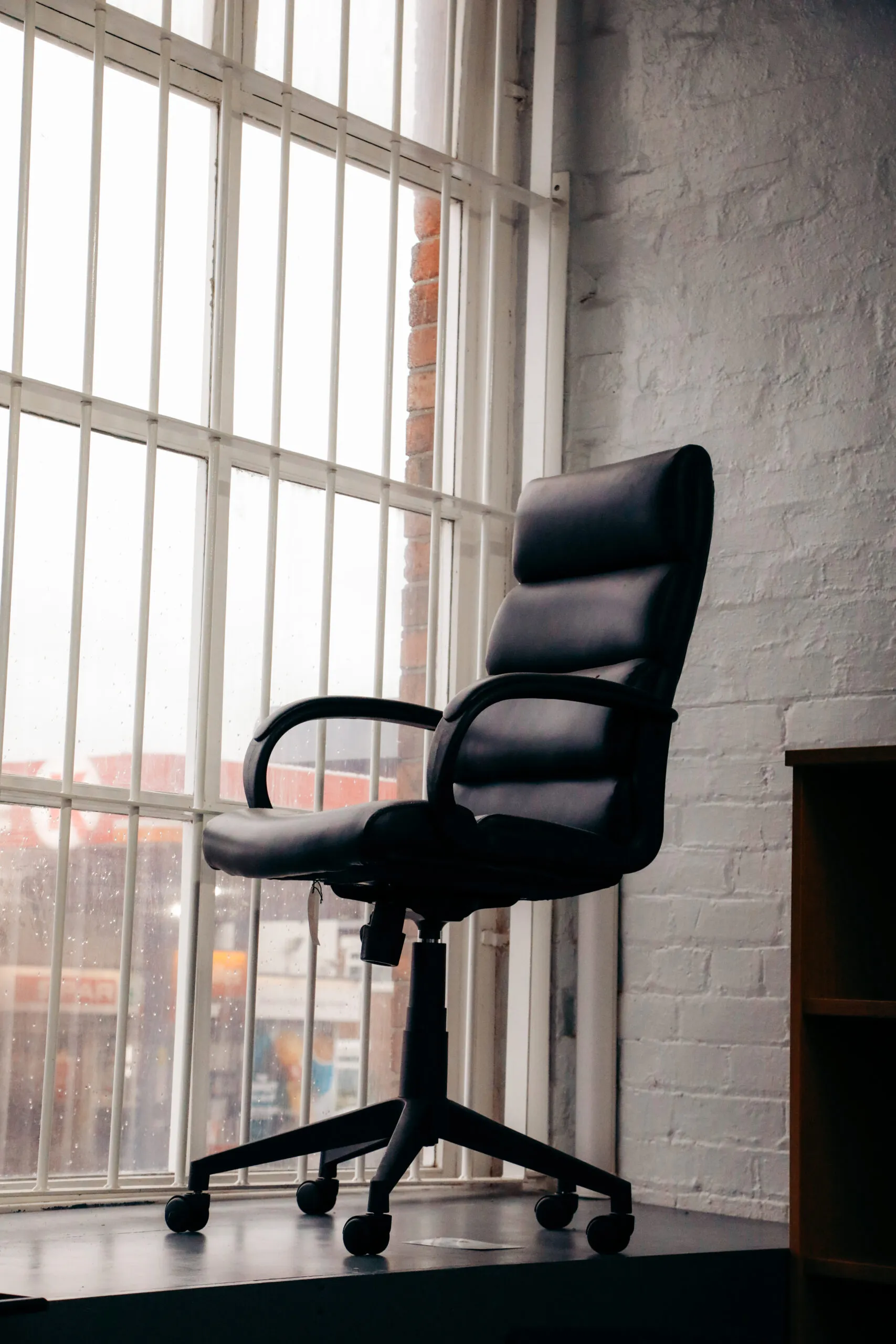 Black leather executive chair by a tall mill window