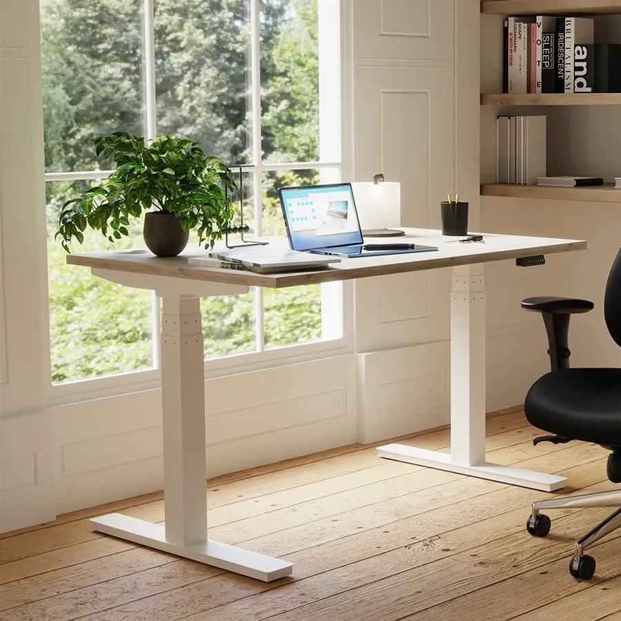 White height adjustable desk with a laptop by a window