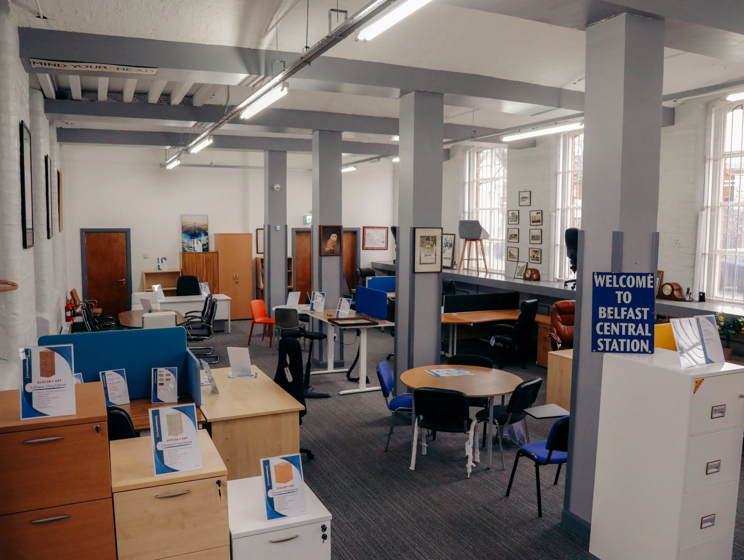 Showroom floor with desks and chairs beside a Belfast Central Station sign
