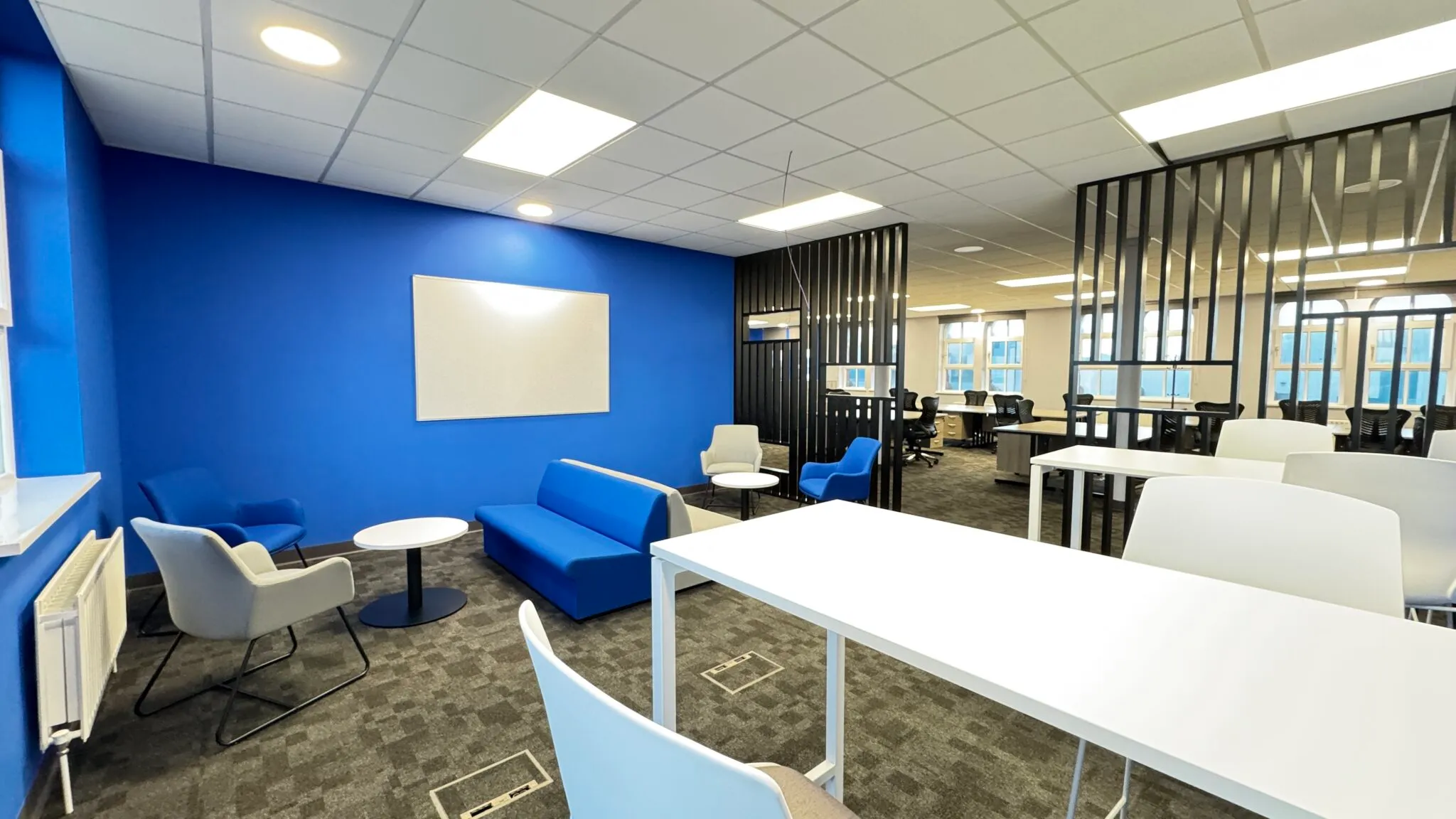 Breakout area with a blue sofa, armchairs and poseur tables