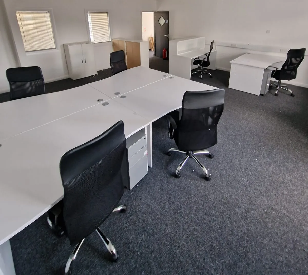 White bench desks with black mesh chairs in an open-plan office
