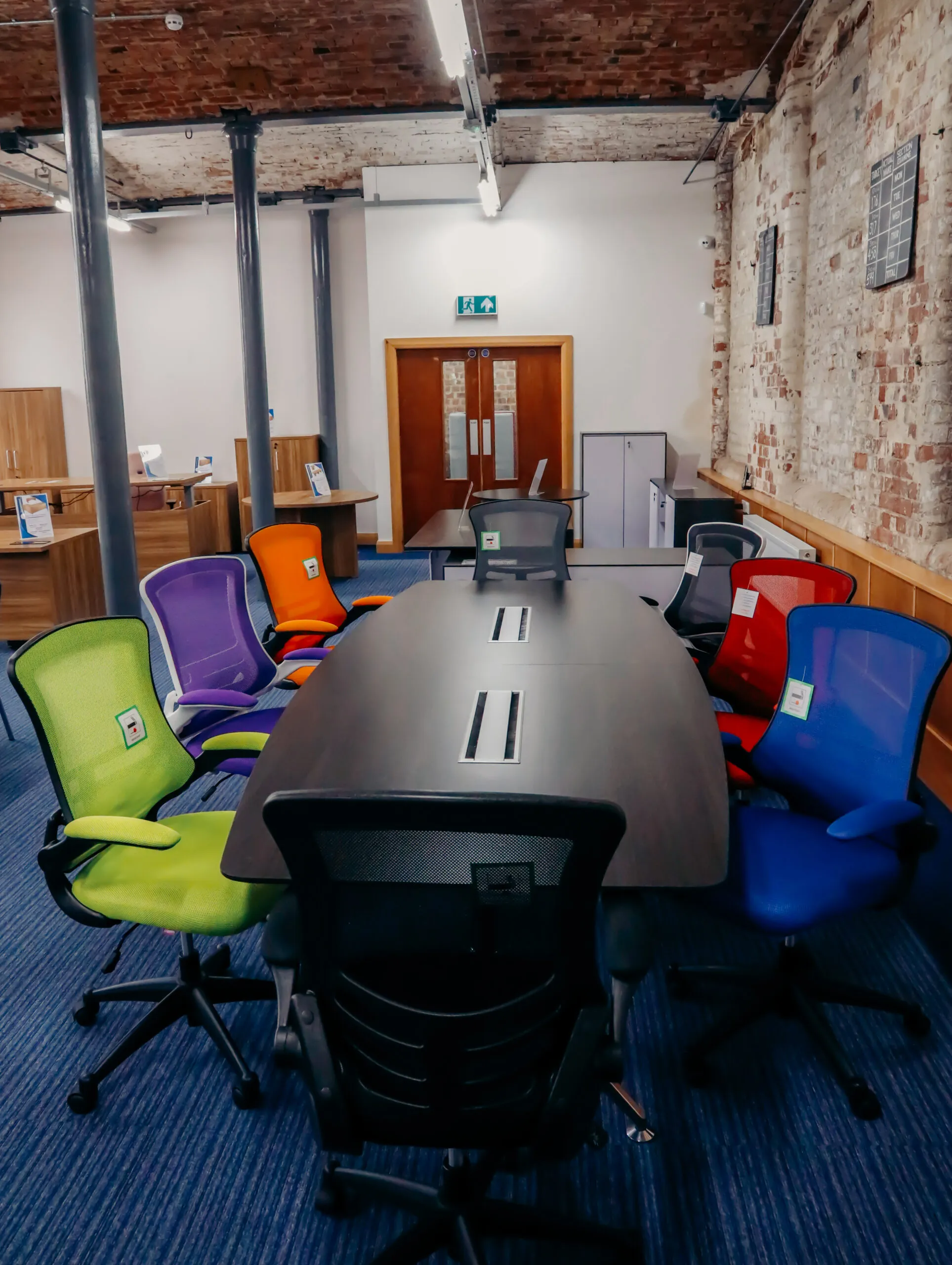 Boardroom table with green, purple, red and blue chairs
