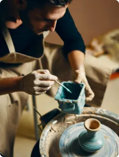Potter glazing a vase on a banding wheel