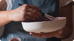 Painting glaze onto a white bowl with a fine brush