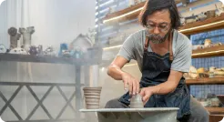Potter throwing a pot on the wheel in a sunlit studio